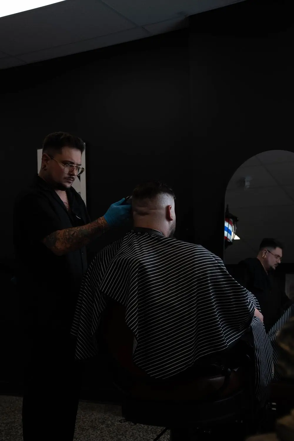 Joey Ouellet doing a clipper fade at Le Barbier Privé, in front of the arched mirror